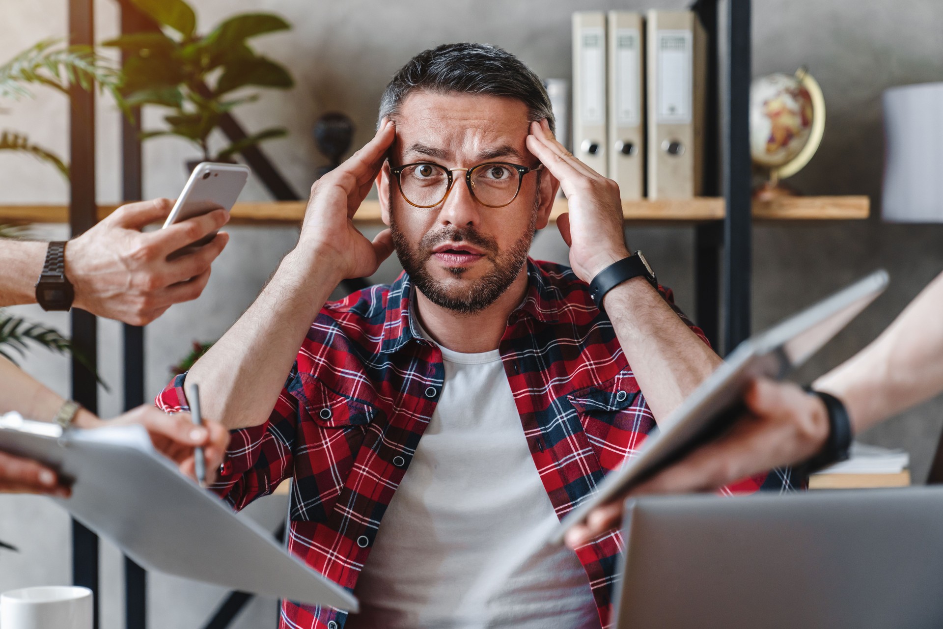 Overworked businessman sitting at laptop overloaded with work multiple tasks in modern office